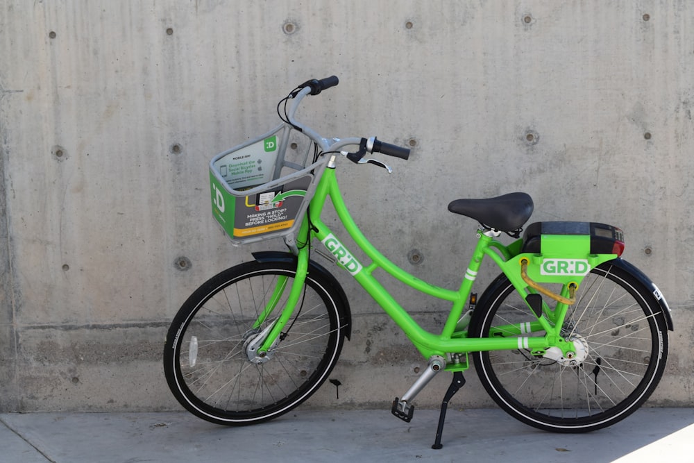 green GR:D bicycle parked beside gray concrete wall during daytime