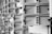 A series of open mailboxes are aligned in a repeating pattern, with barcodes visible on the inside of some doors. The scene is captured in black and white, emphasizing the metal texture and geometrical design.