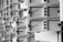A series of open mailboxes are aligned in a repeating pattern, with barcodes visible on the inside of some doors. The scene is captured in black and white, emphasizing the metal texture and geometrical design.