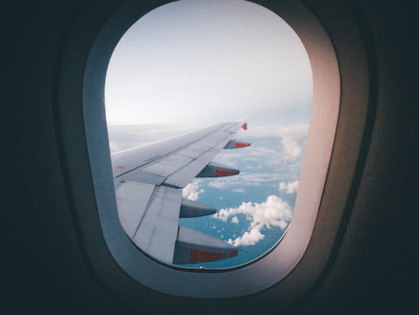 Flight view from airplane window showing clouds and horizon.