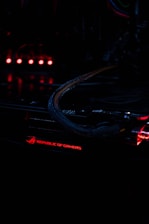 Close-up of a high-performance gaming PC motherboard illuminated with orange and black LED lights in a sleek modern setup.
