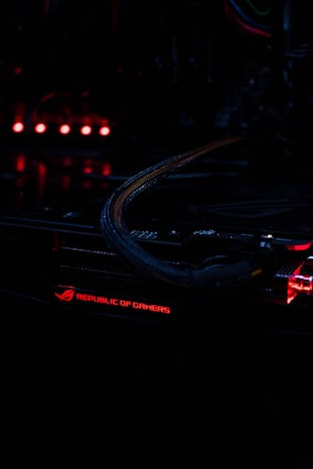 Close-up of a high-performance gaming PC motherboard illuminated with orange and black LED lights in a sleek modern setup.