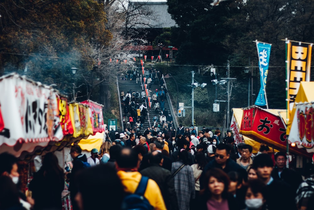 a crowd of people walking down a street next to banners