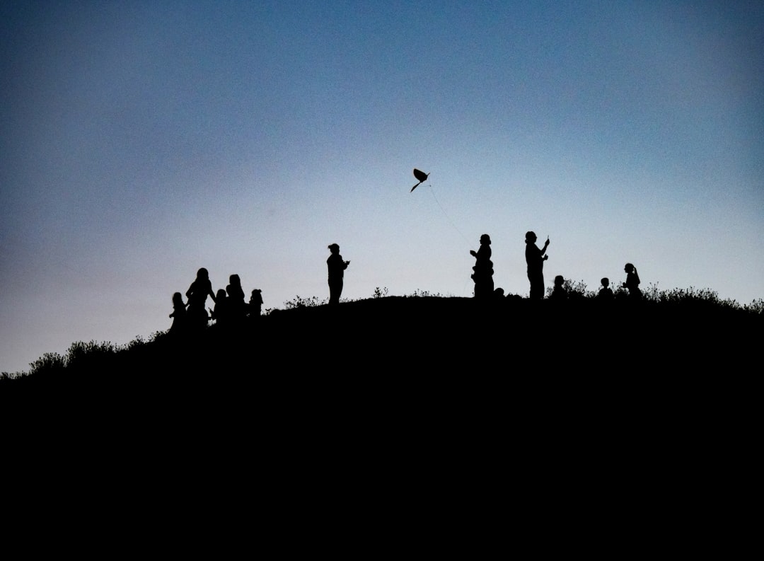 silhouette photography of people on top of a land formation