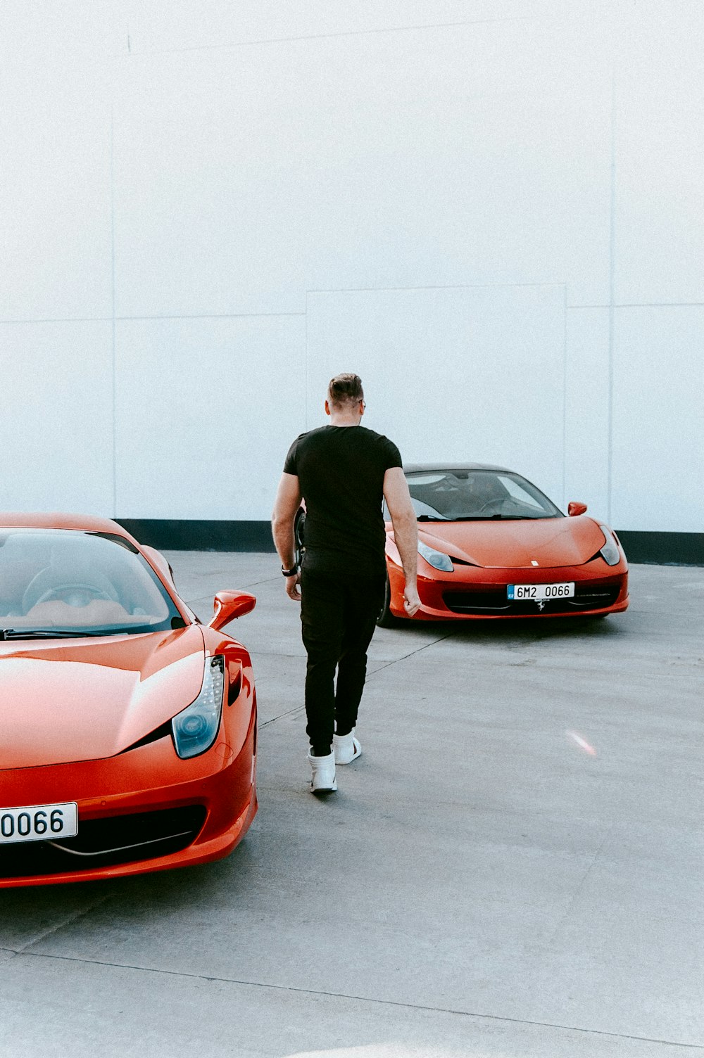 man walking between red vehicles