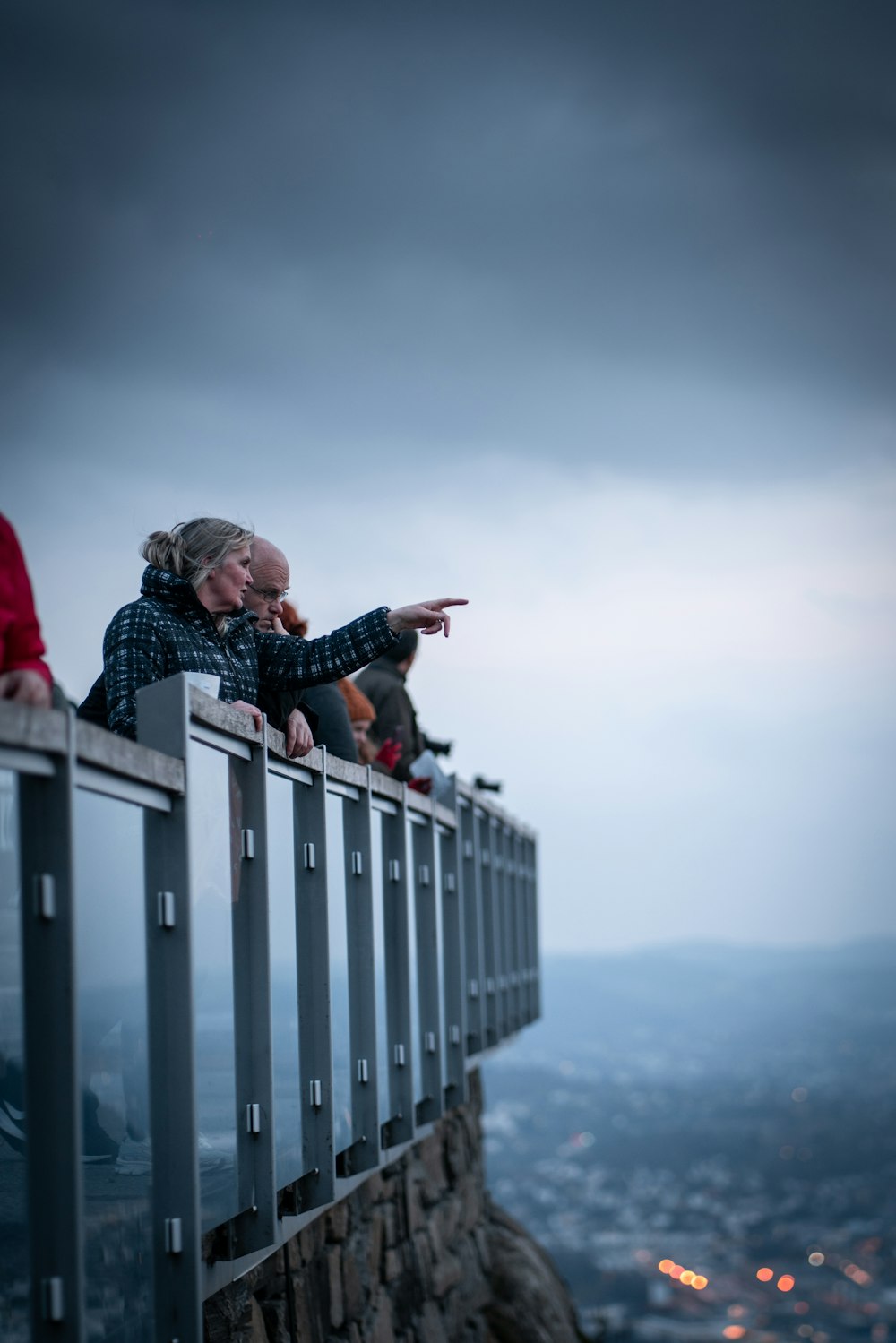 man and woman leaning on a glass railing