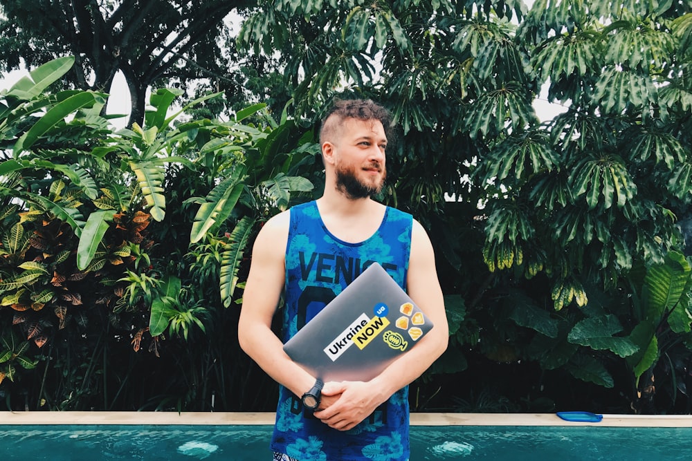 man wearing blue tank top near green tree