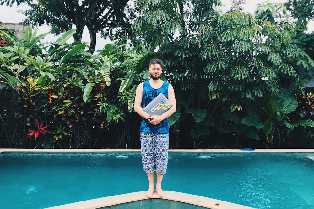 Mann in blauem Tanktop steht auf Pool