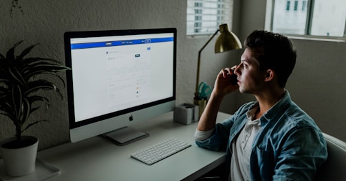 man in blue denim jacket facing turned on monitor