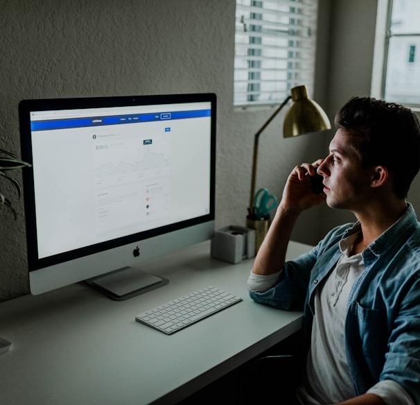 man in blue denim jacket facing turned on monitor