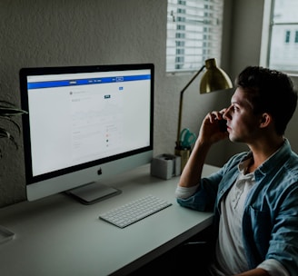 man in blue denim jacket facing turned on monitor