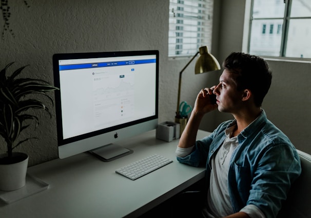 man in blue denim jacket facing turned on monitor