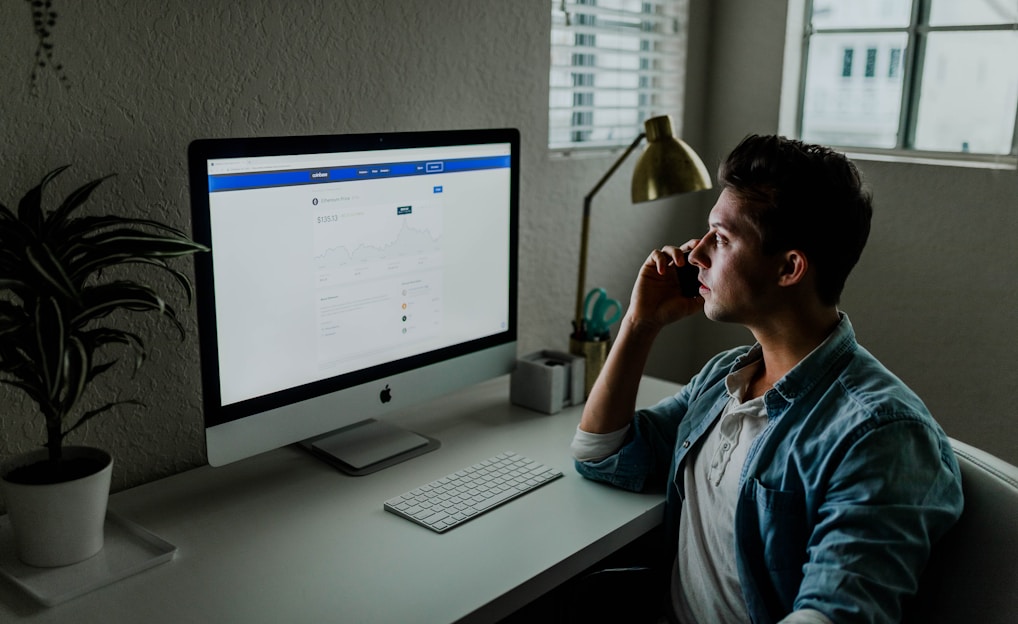 man in blue denim jacket facing turned on monitor