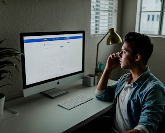 man in blue denim jacket facing turned on monitor