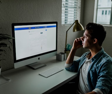 man in blue denim jacket facing turned on monitor