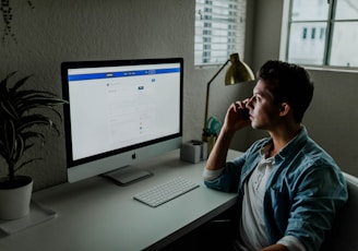 man in blue denim jacket facing turned on monitor