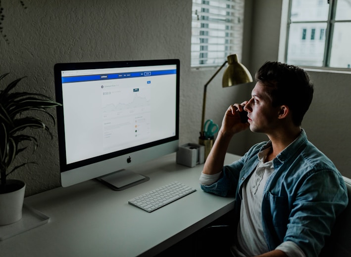 man in blue denim jacket facing turned on monitor