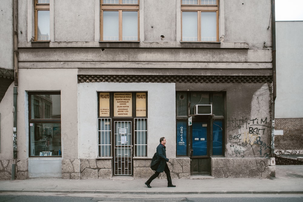 man wearing black coat walking on street