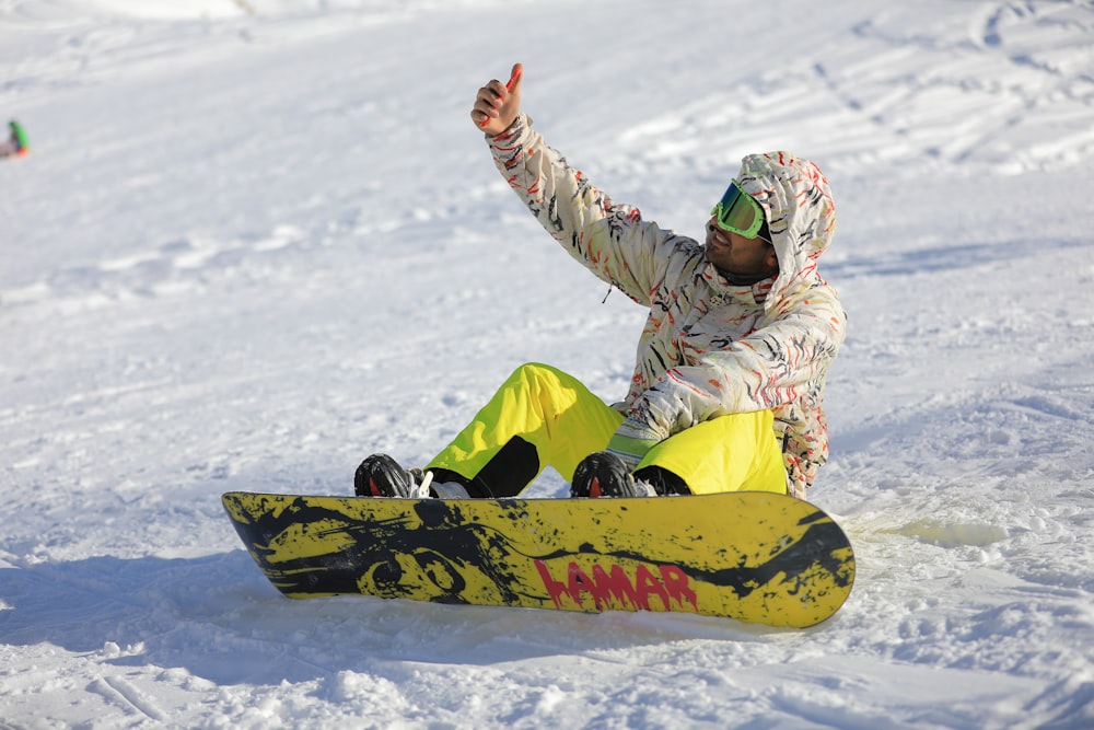 person wearing gray and white jacket riding yellow and red snowboard