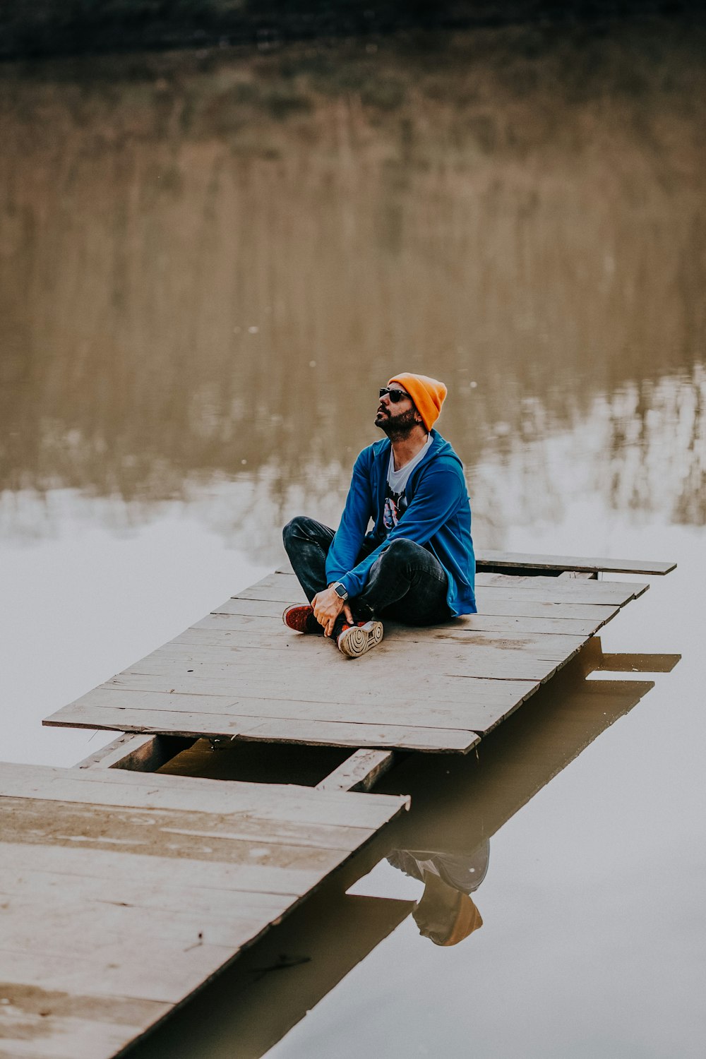 man sitting on wooden dock