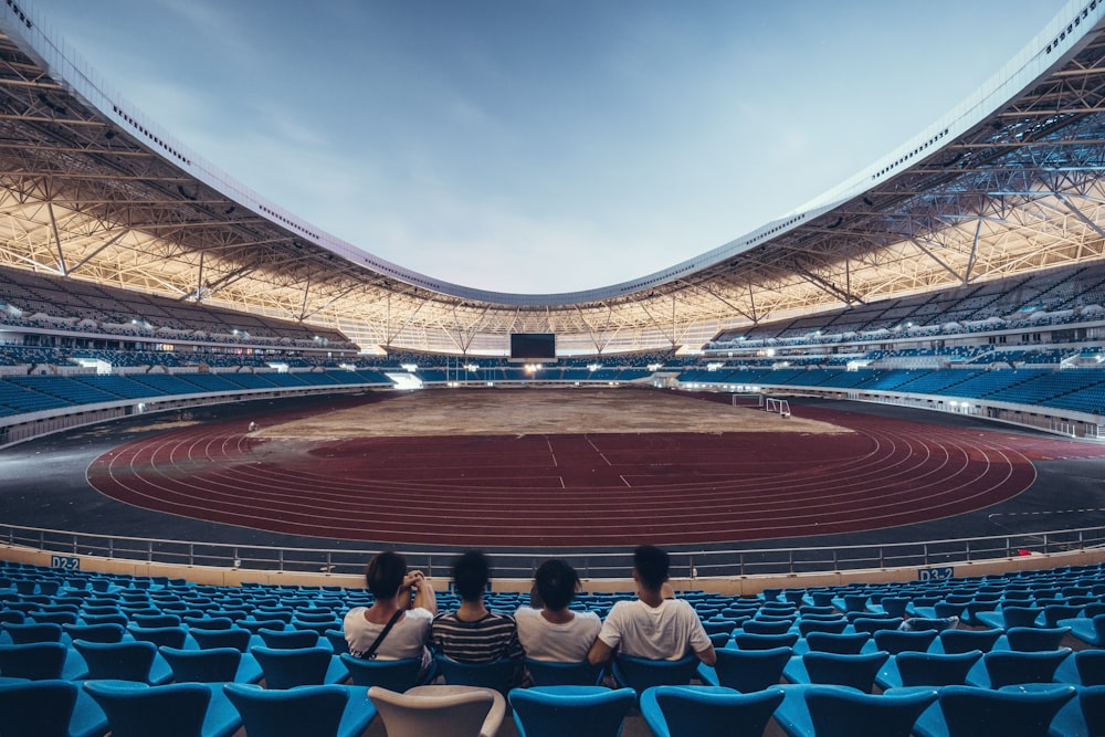 Cuatro personas sentadas en el estadio de la silla azul