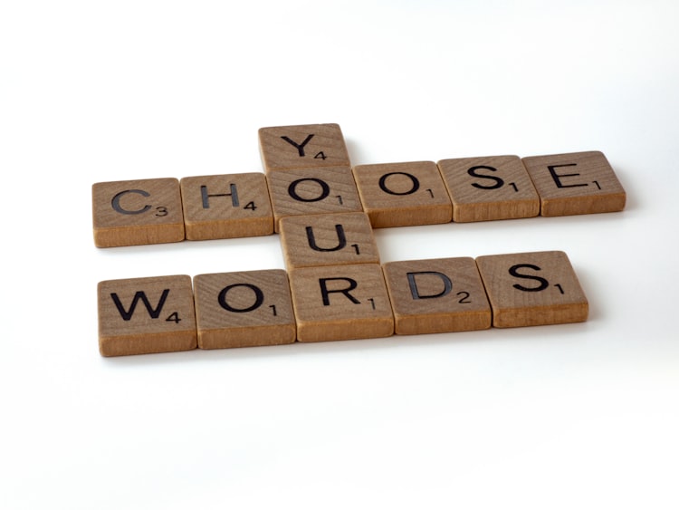 A photo of Scrabble pieces arranged to read "Choose Your Words".