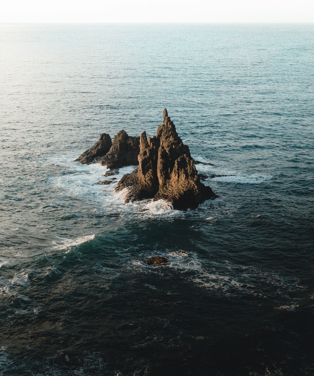 brown rock formation in body of water