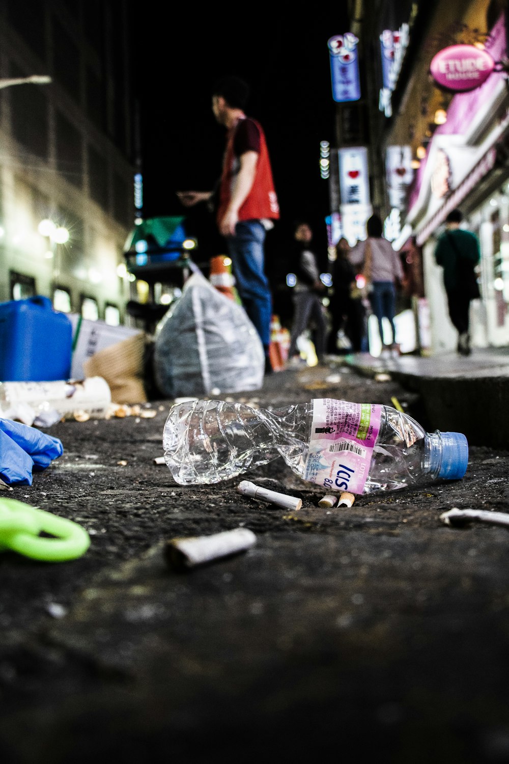 shallow focus photography of clear plastic bottle and cigarette butts on floor