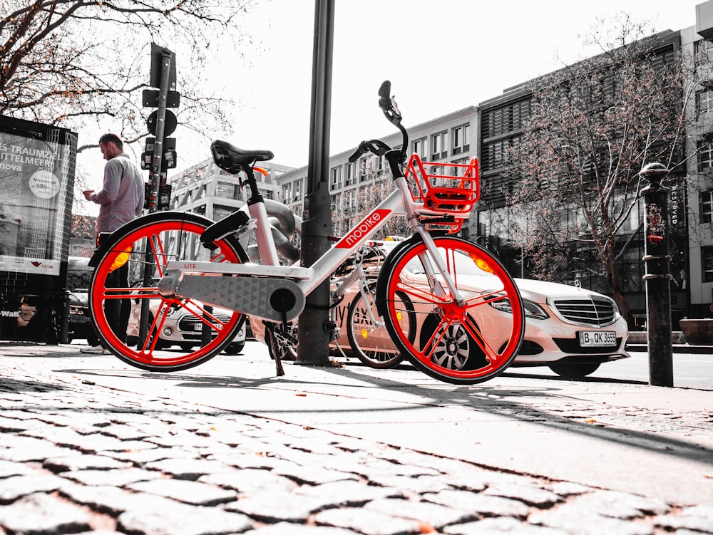 흰색과 빨간색 자전거가 기둥 근처에 주차되어 있습니다.
