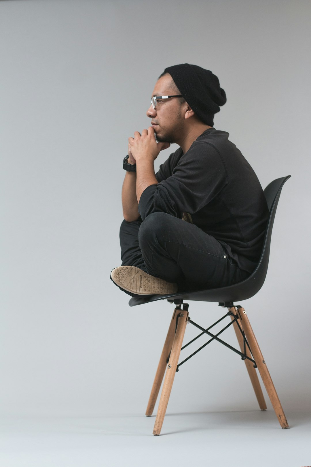 Guy with glasses sitting in a chair, deep in thought