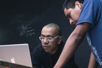 two men watching on silver MacBook