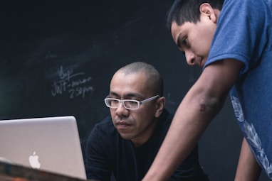 two men watching on silver MacBook