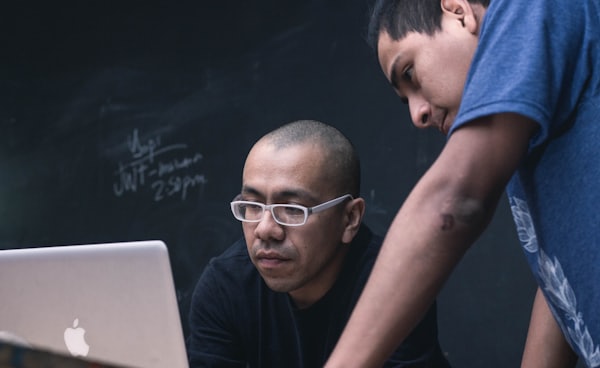 two men watching on silver MacBook