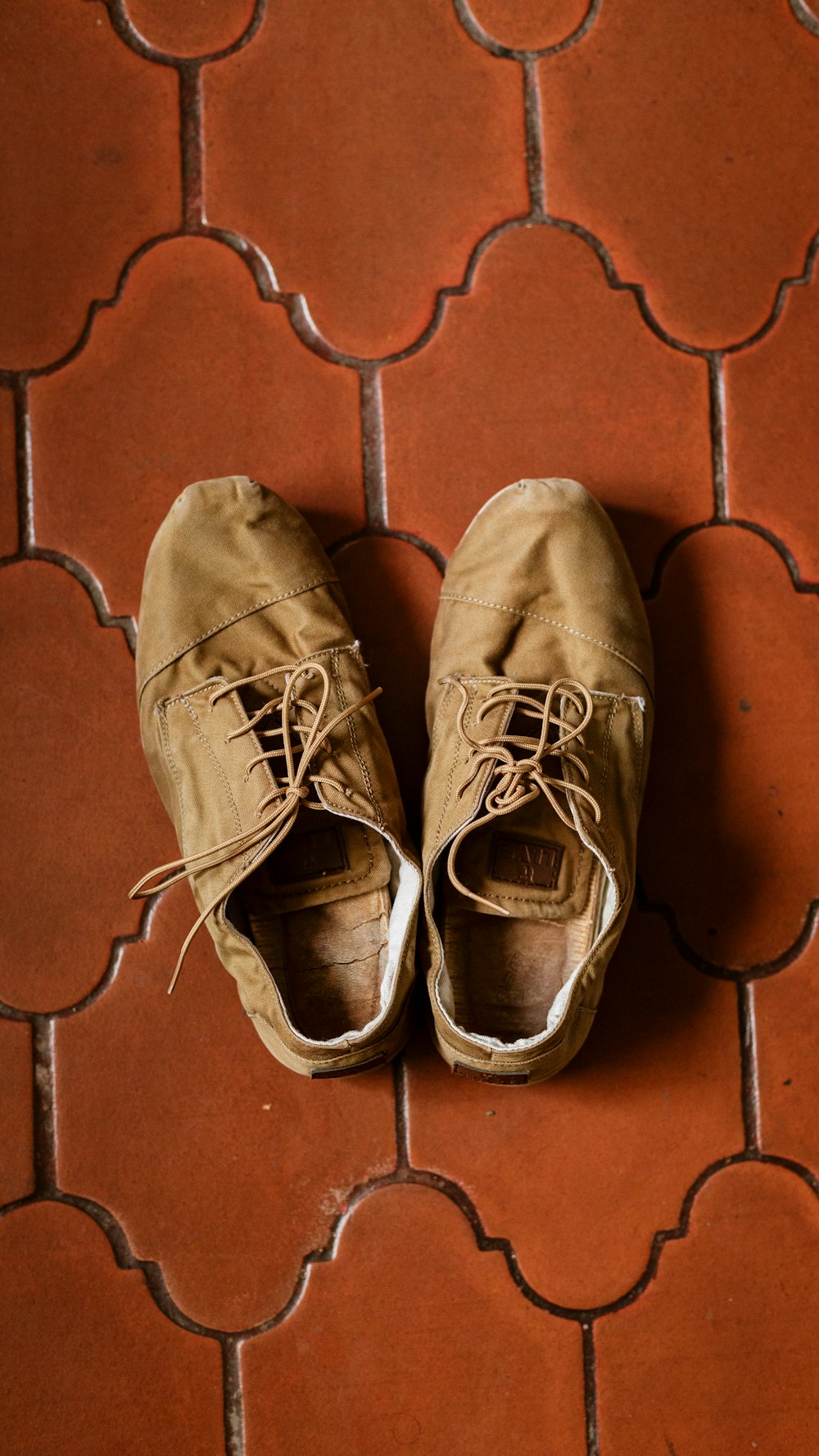 Par de zapatillas bajas de gamuza marrón sobre superficie marrón