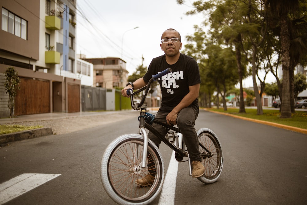 man riding BMX bike at middle of road during daytime