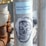 A metallic pole featuring a blue sticker with the phrase 'Helping Others Helps Yourself' and a black stencil art depiction of a face resembling a mask or skull.