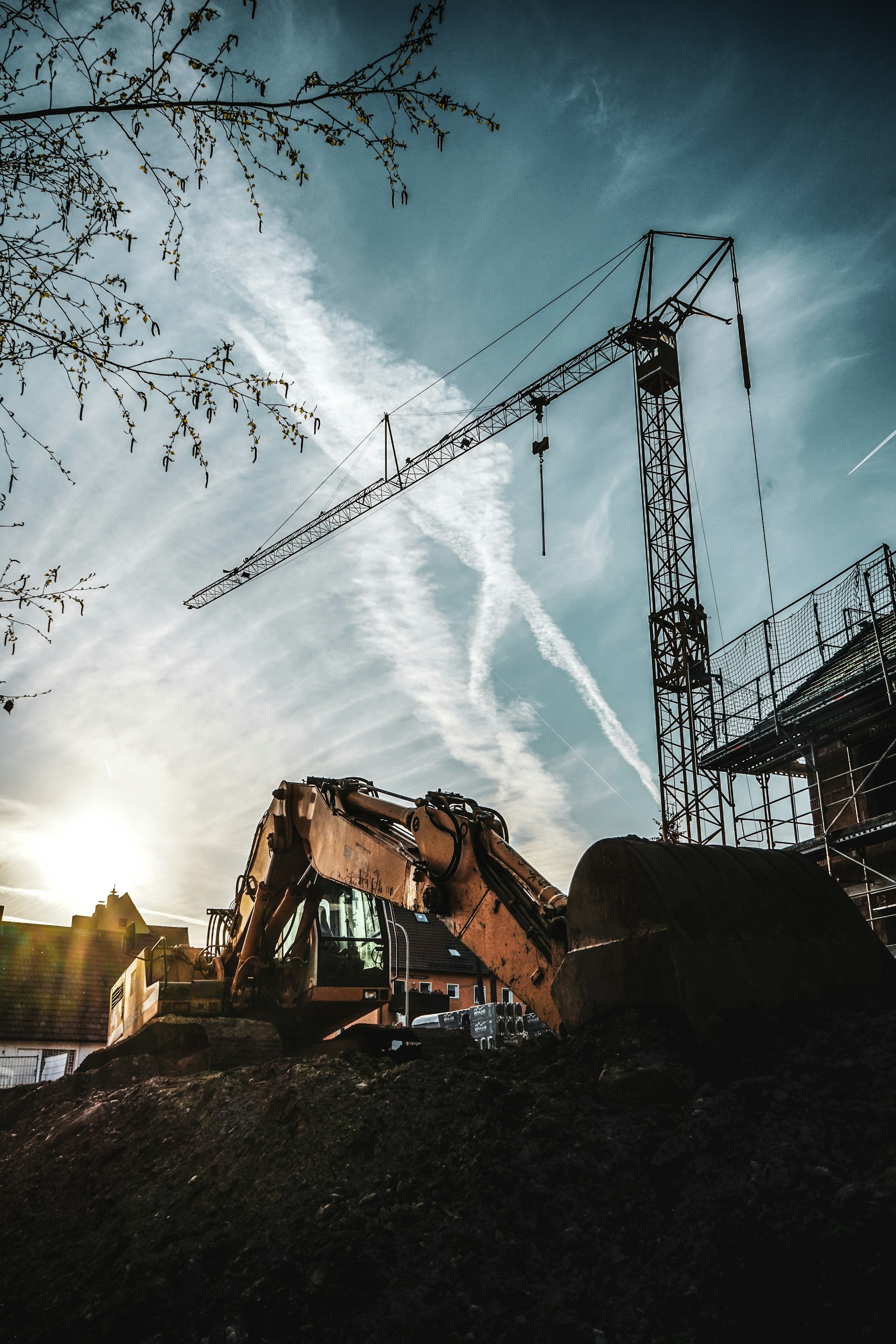 A dynamic construction site at sunset showing workers and heavy machinery in action, highlighting the energy and expertise of crc (construcciones rivera de la cruz).