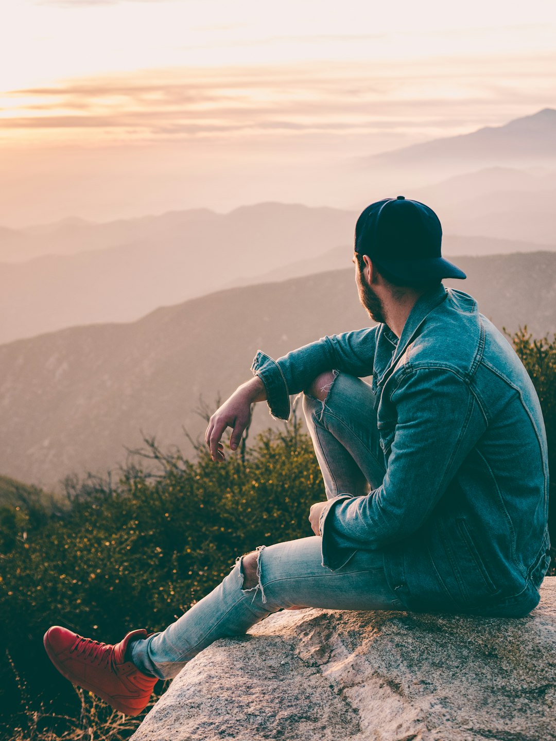 man sitting on gray rock