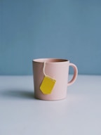 A light pink mug on a white table against a blue background