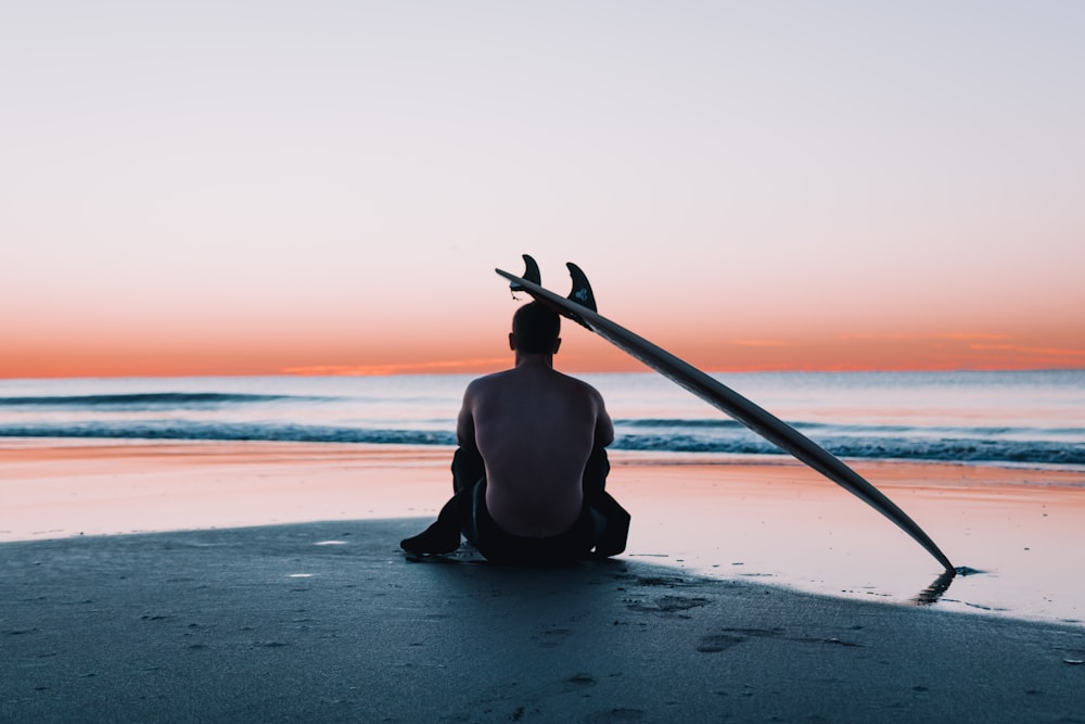 man sitting on the sand in front of sea