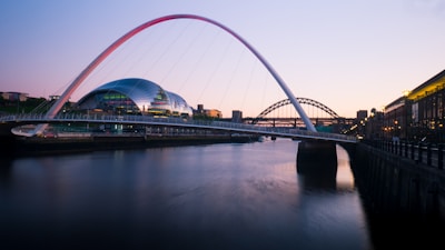 A modern bridge arching gracefully over a river at sunset.