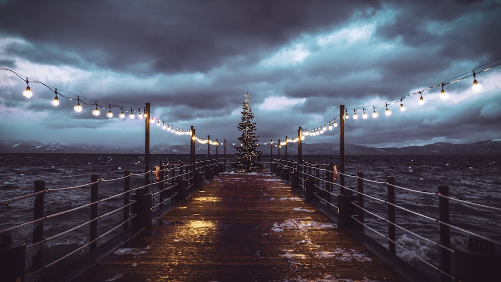 footbridge leading to the sea during nighttime with dramatic sky