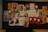 A collage of posters and images on a wall, featuring a mix of pop culture and political references. Notable elements include depictions of Godzilla, the 'Obey' motif with an octopus, Che Guevara's portrait, and the masked, smiling face associated with 'F Society' and the popular anonymous mask. Stormtrooper graphics are present, as well as various posters with slogans and symbols of resistance.