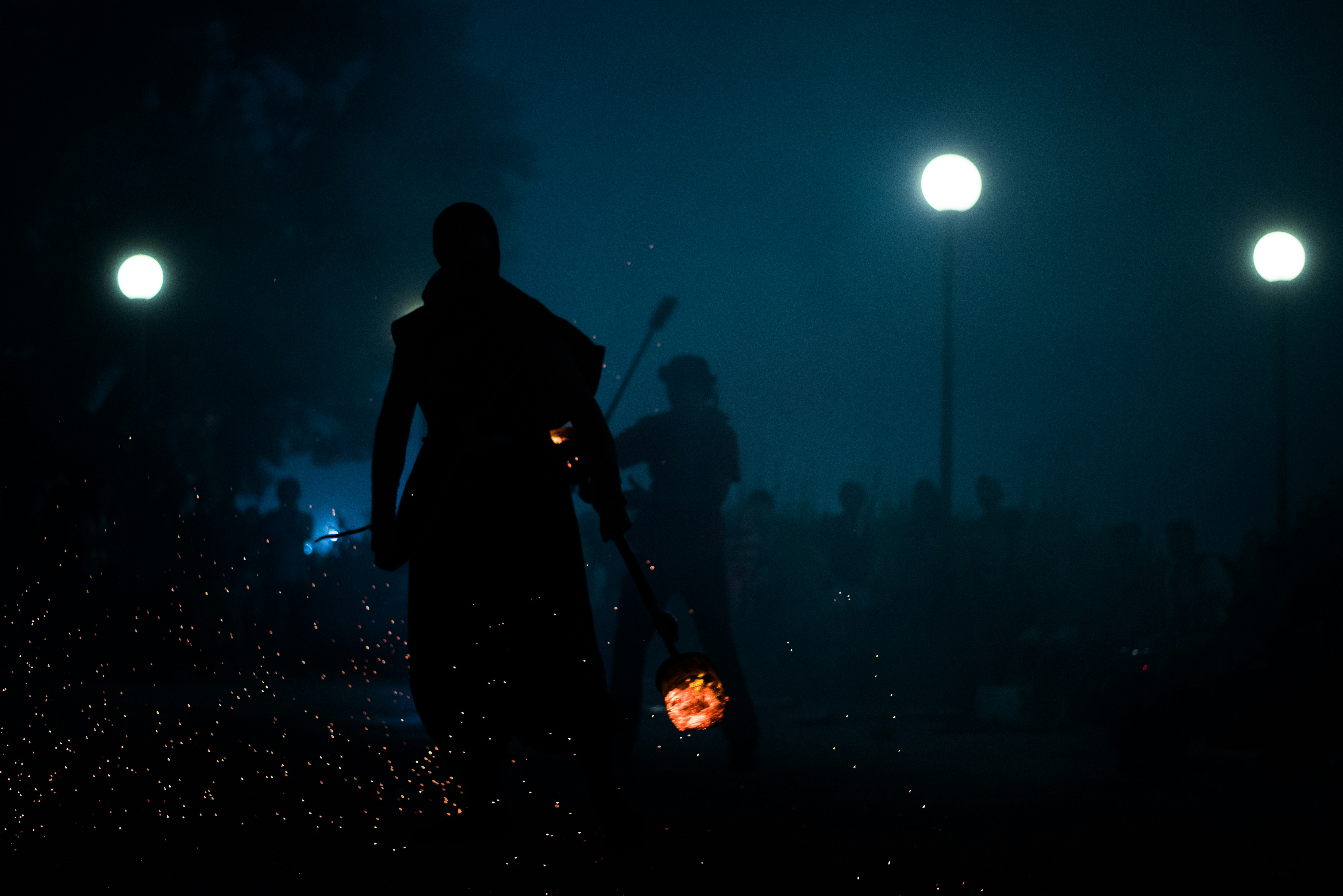 silhouette of person holding burning wood at night