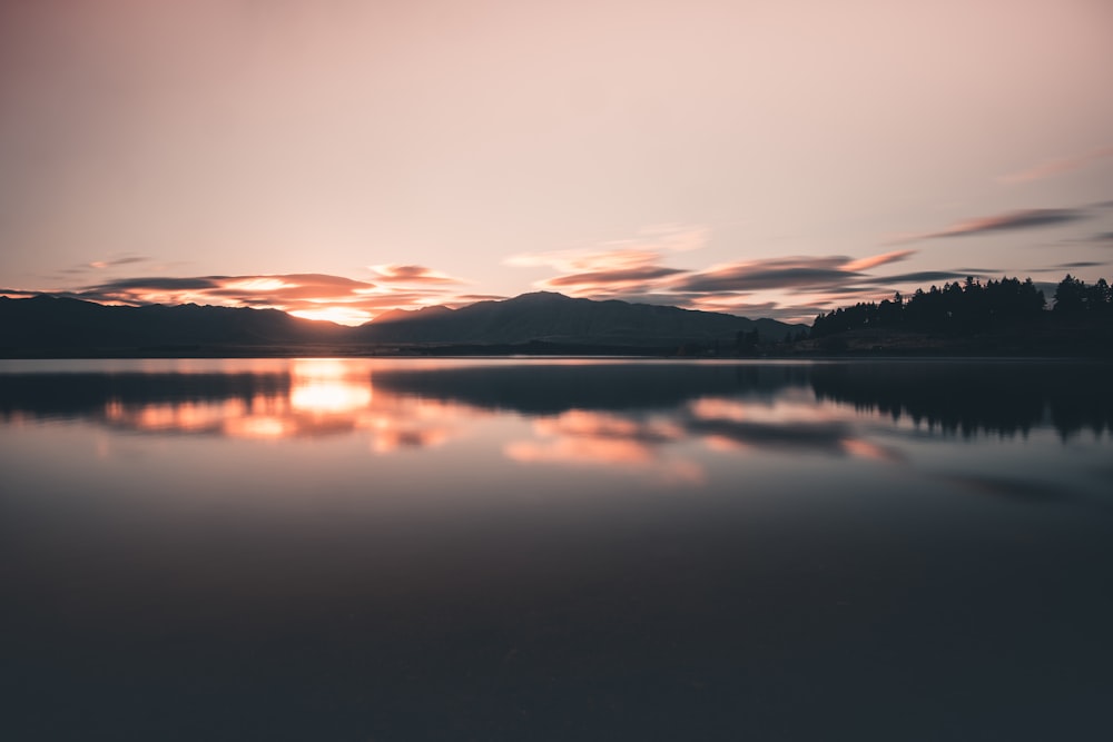 calm body of water near the mountain during golden hour