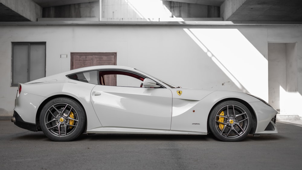 white coupe beside white painted building