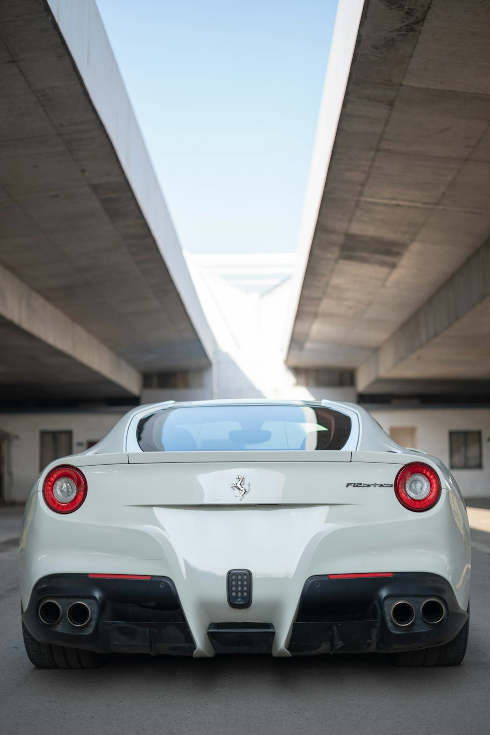 veículo Ferrari branco estacionado sob ponte