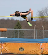 A young athlete mid-air during a triple jump practice session.