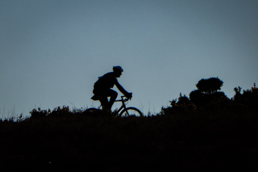 silhouette of man biking on mountain