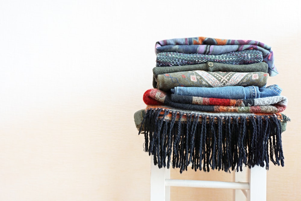 pile of clothes on white wooden stool